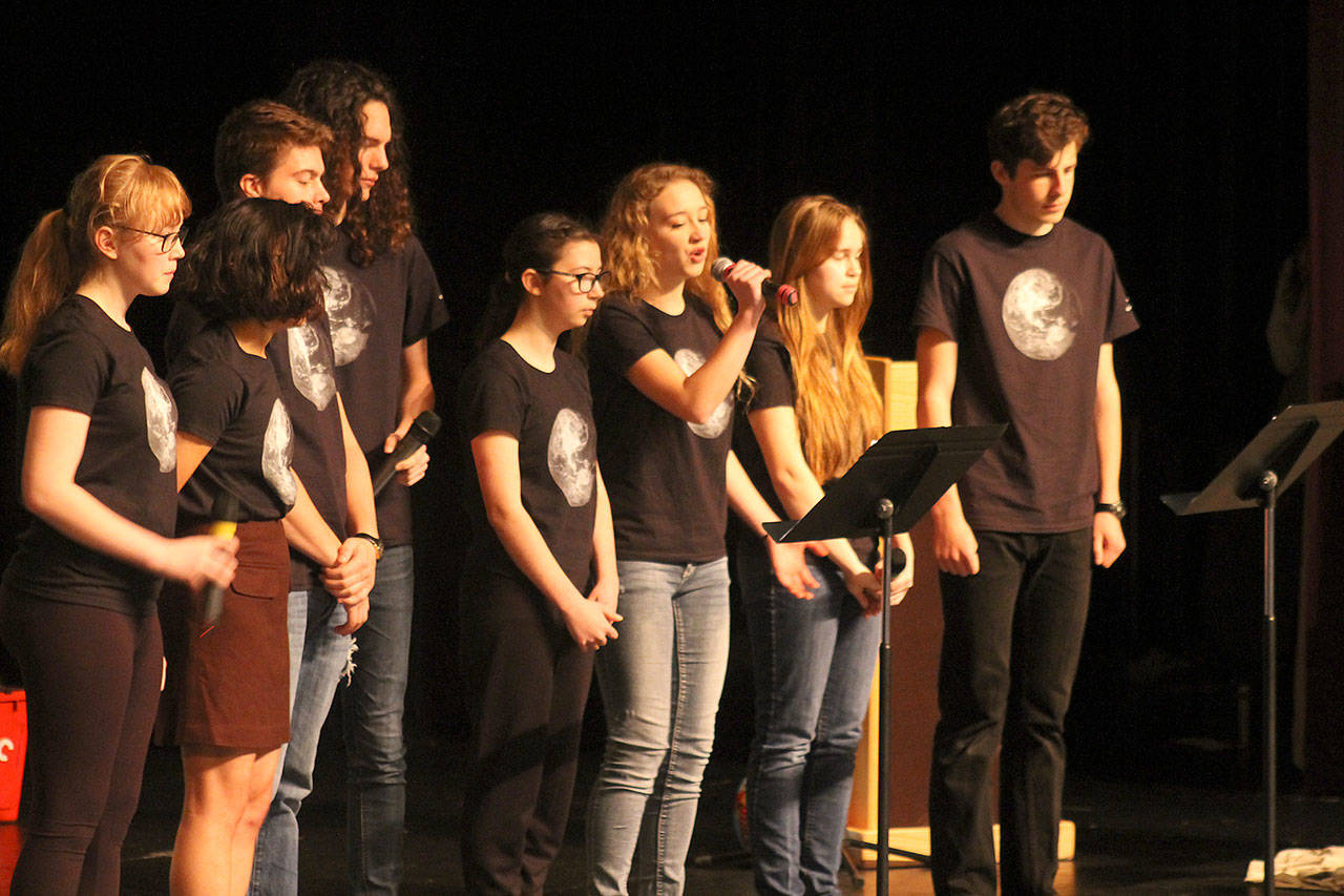 Evan Thompson / The Record &mdash; Kari Hustad, with microphone, sings during the Climate Arts Project&rsquo;s performance on Wednesday morning in South Whidbey High School&rsquo;s auditorium.