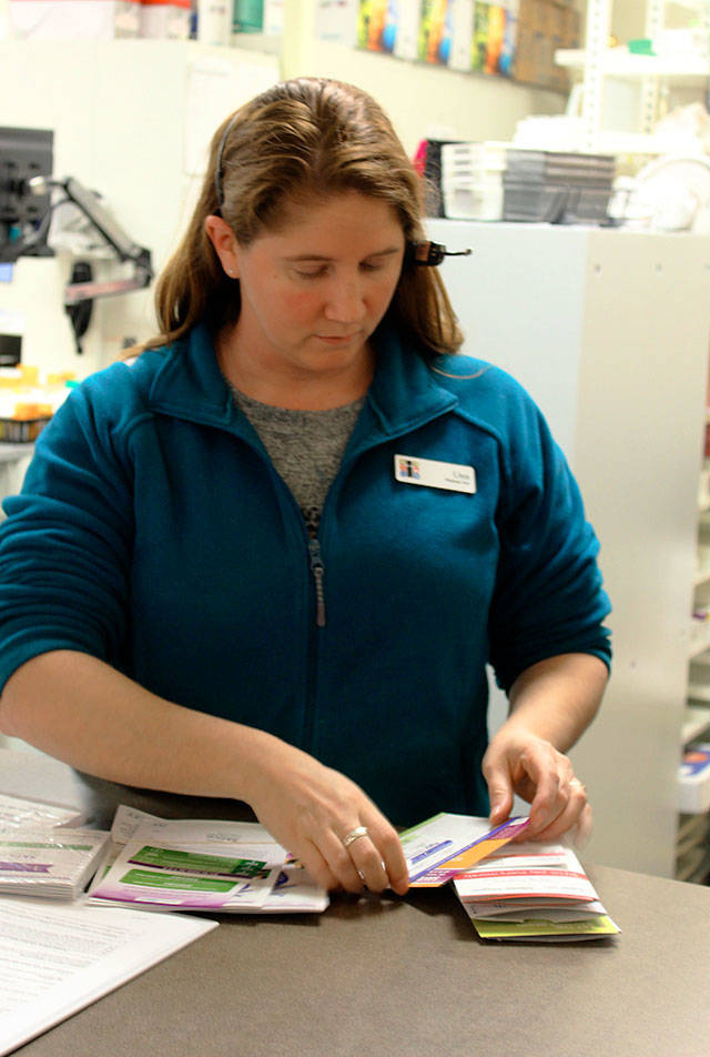 Patricia Guthrie / Whidbey News-Times — At Island Drug in Oak Harbor, pharmacy tech Lisa Bacolo sorts through the many prescription cards customers bring. in