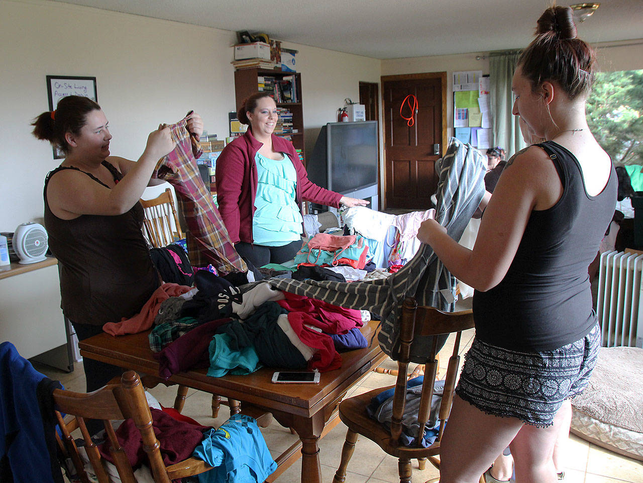 Photo by Jessie Stensland / Whidbey News-Times                                Liz Mickelson, Nikki Shorb and Anna Cavender, from left, sort clothes at a drop-in center at Ryan&rsquo;s House for Youth in Coupeville. The center has a clothes closet where young people can take clothes and other items they need.