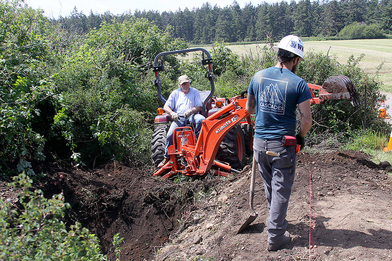 Craig Holmquist uses an excavator Monday, May 22, 2017 to dig a hole for a new vault toilet that will be installed in June near the office of Ebey’s Landing National Historical Reserve in Coupeville. Carl Sholin, an archaeologist with the National Park Service, monitors the dig. The Reserve will be busy with several projects this summer as it braces for an increasing number of visitors. Photo by Ron Newberry/Whidbey News-Times