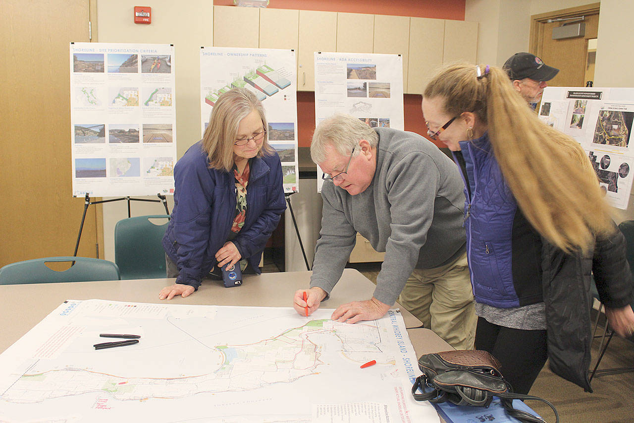 Patricia Guthrie / Whidbey News Group &mdash; Residents look over maps for possible additions to hiking, biking and beach areas on Whidbey Island during public meetings this winter. A second round of meetings take place in June on the non-motorized trail plan. County planner Brian Wood explains the bike trail system at a Coupeville meeting earlier this year.