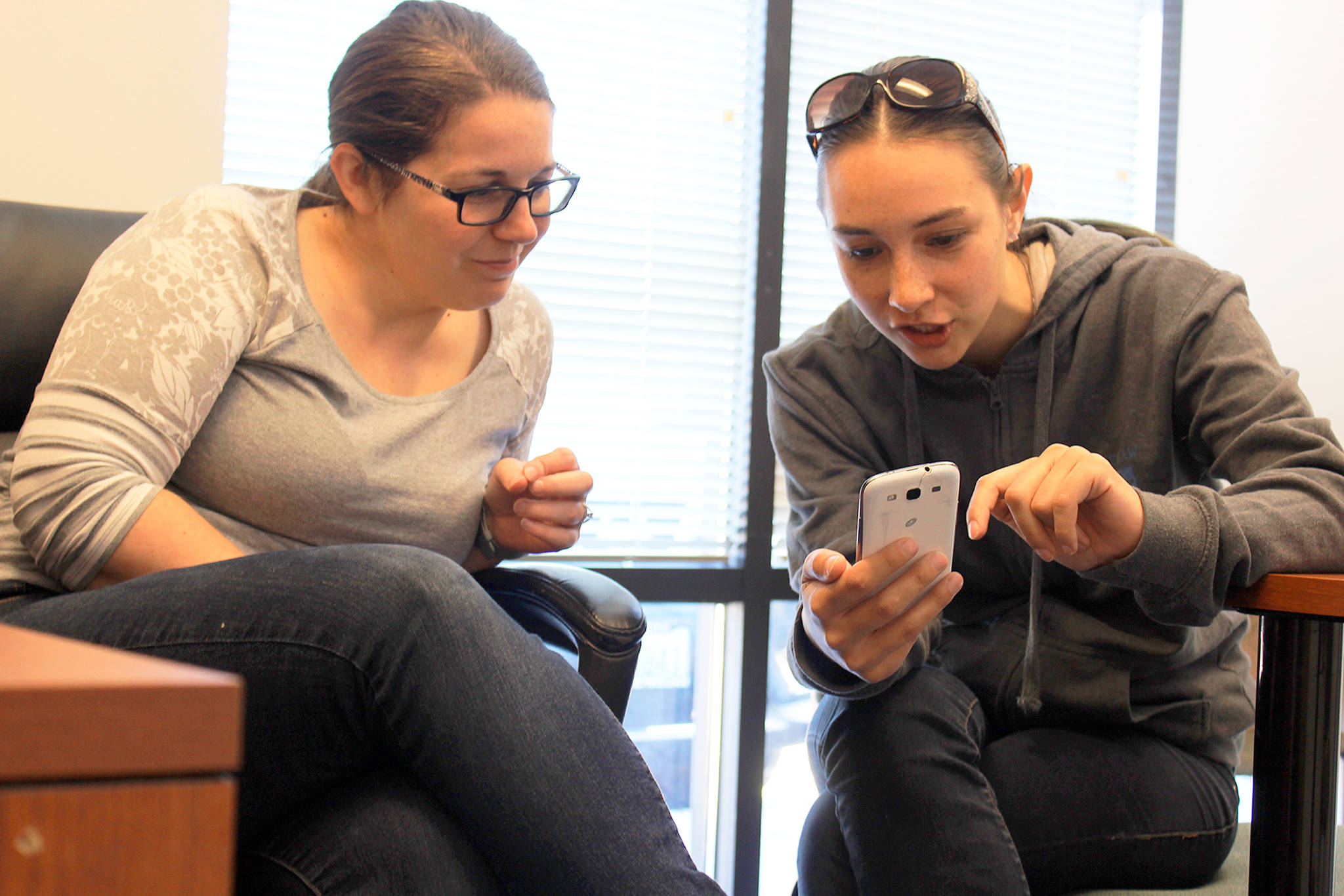 At the Compass Health Oak Harbor office, client Amanda Buchanan shows photos of her son to Ryan O&rsquo;Donnell, supervisor of a team of mental health therapists who visited Buchanan, her son and family at home for the past year.                                Photo by Patricia Guthrie/Whidbey News-Times