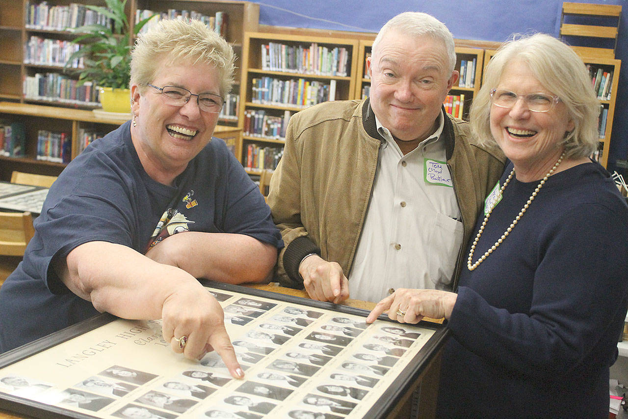 Evan Thompson / The Record — Sharon Cattron Edwards, left, and Nedra Floyd Paulter point to their 1966 senior class photos during the farewell event at Langley Middle School on Friday. Floyd Paulter’s husband, Tom, is in the middle.