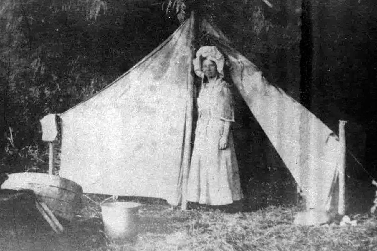 Historical image — Minnie Spencer-Plumb stands in front of a tent at Honeymoon Bay, the place she honeymooned in 1909. It’s been named Honeymoon Bay ever since.