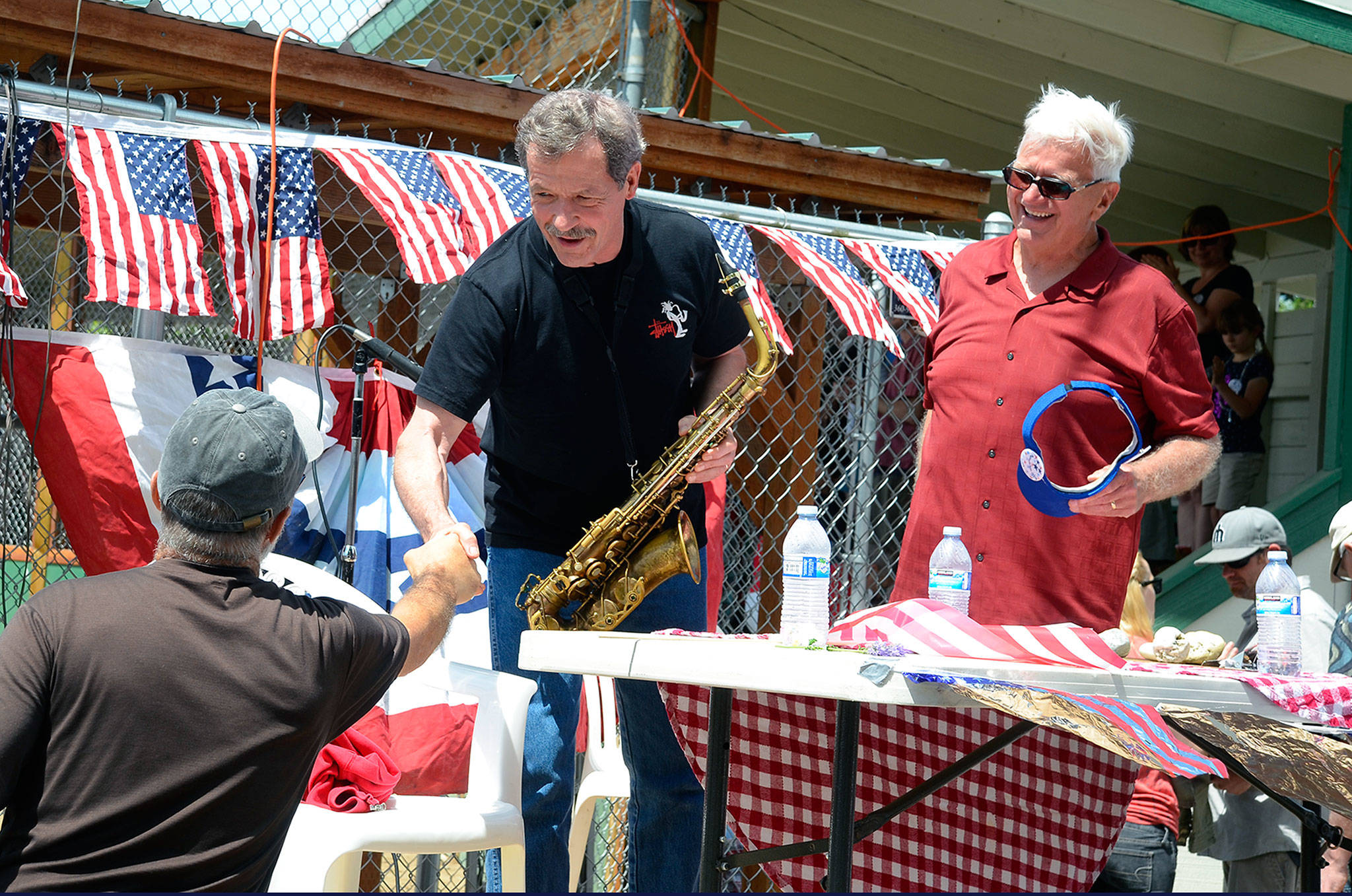 Record file — Danny Ward shakes the hand of a Maxwelton Independence Day Parade attendee in 2014. He’s been playing The National Anthem at the annual event for years and is the 2017 grand marshal.