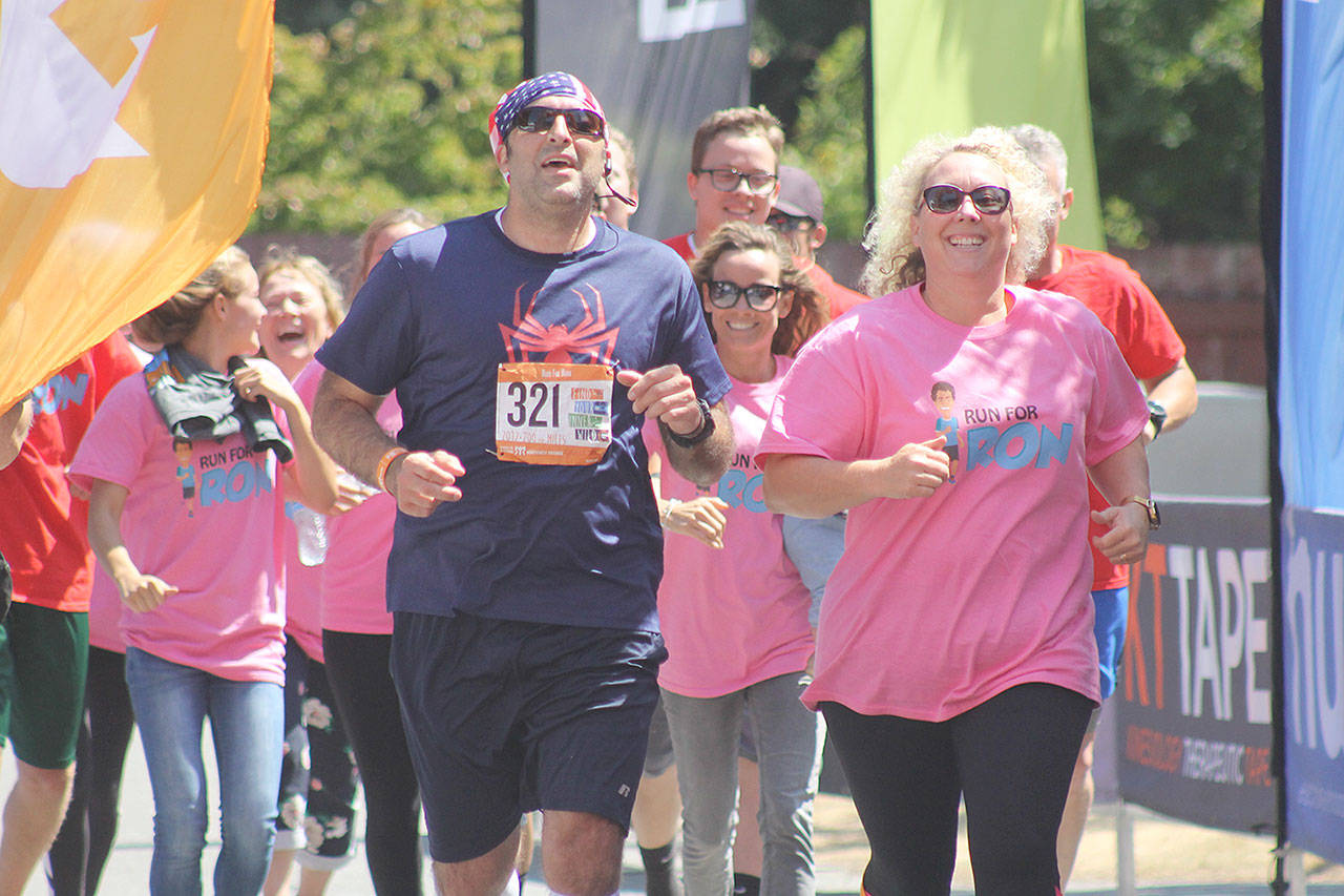 Evan Thompson / The Record — Mickey Nelson, left, runs to the finish line with his Run for Ron teammates on Saturday. The Northwest Passage Ragnar Relay began in Blaine on July 14 and ended at the Island County Fairgrounds on July 15. To Nelson’s left is Cherie Campbell.