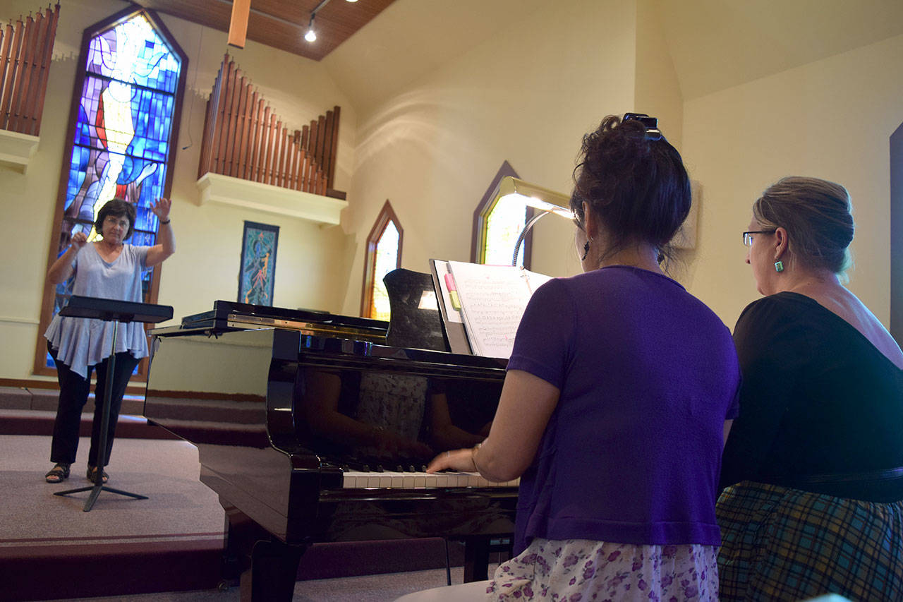 Kyle Jensen / The Record &mdash; Attendee Cathy Humphers Smith conducts two pianists on the opening day of the Pacific Northwest Conducting Institute.