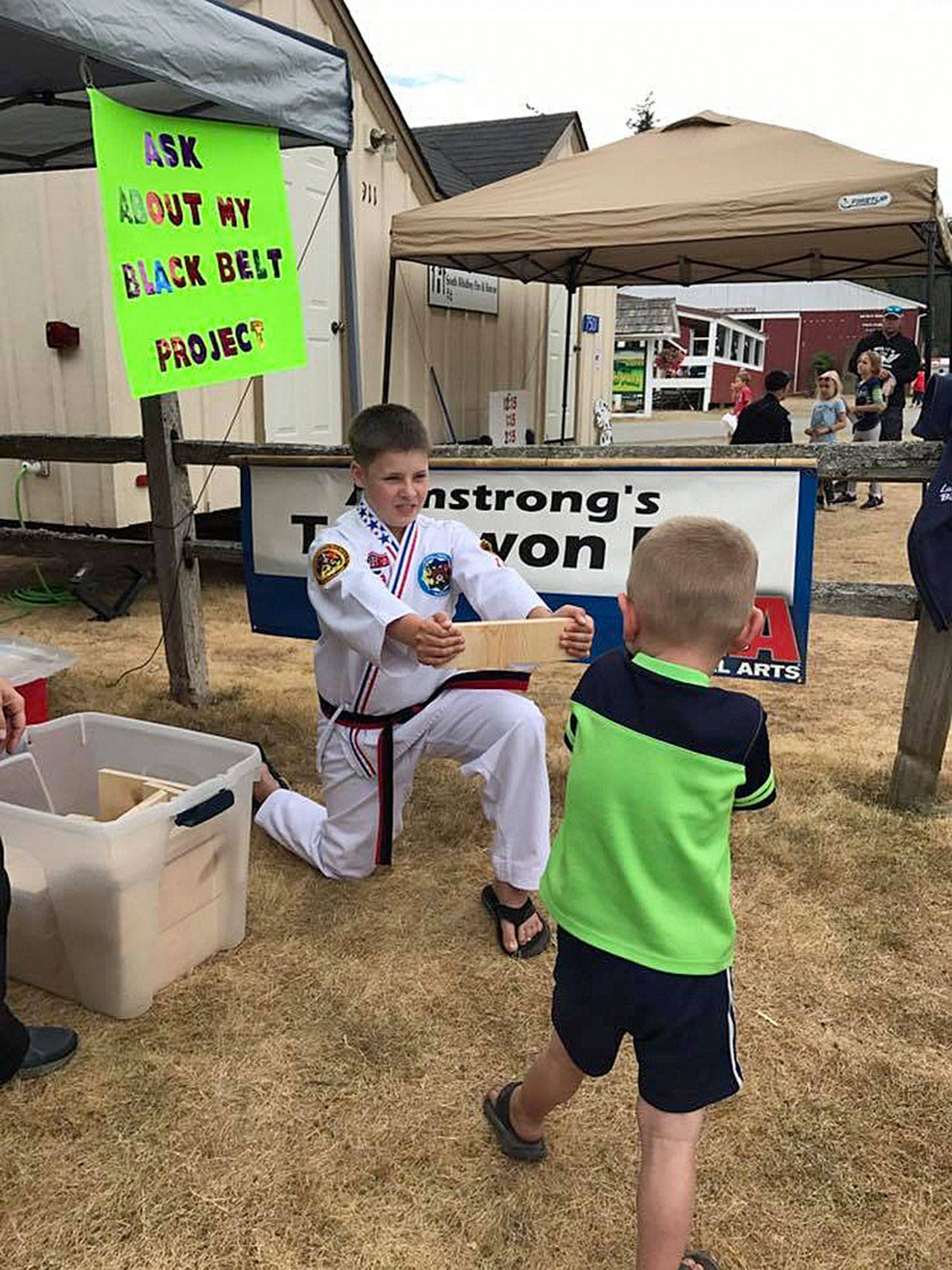 Contributed photo — Freeland resident Nicholas Armstrong holds a wooden board for someone to break at the Whidbey Island Fair.