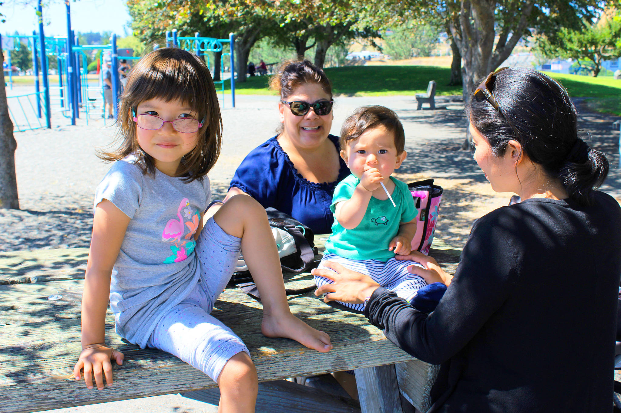 At Windjammer Park, escaping into the shade on Monday, are Venus C. Bemish (wearing sunglasses) and Konomi Fraley with her children, Grace, and Johnny. The Oak Harbor residents had planned to take a long walk along the shore but opted for a cooler spot. Temperatures are expected to drift into the high 80s, maybe 90s on Whidbey this week.                                Photo by Patricia Guthrie/Whidbey News-Times