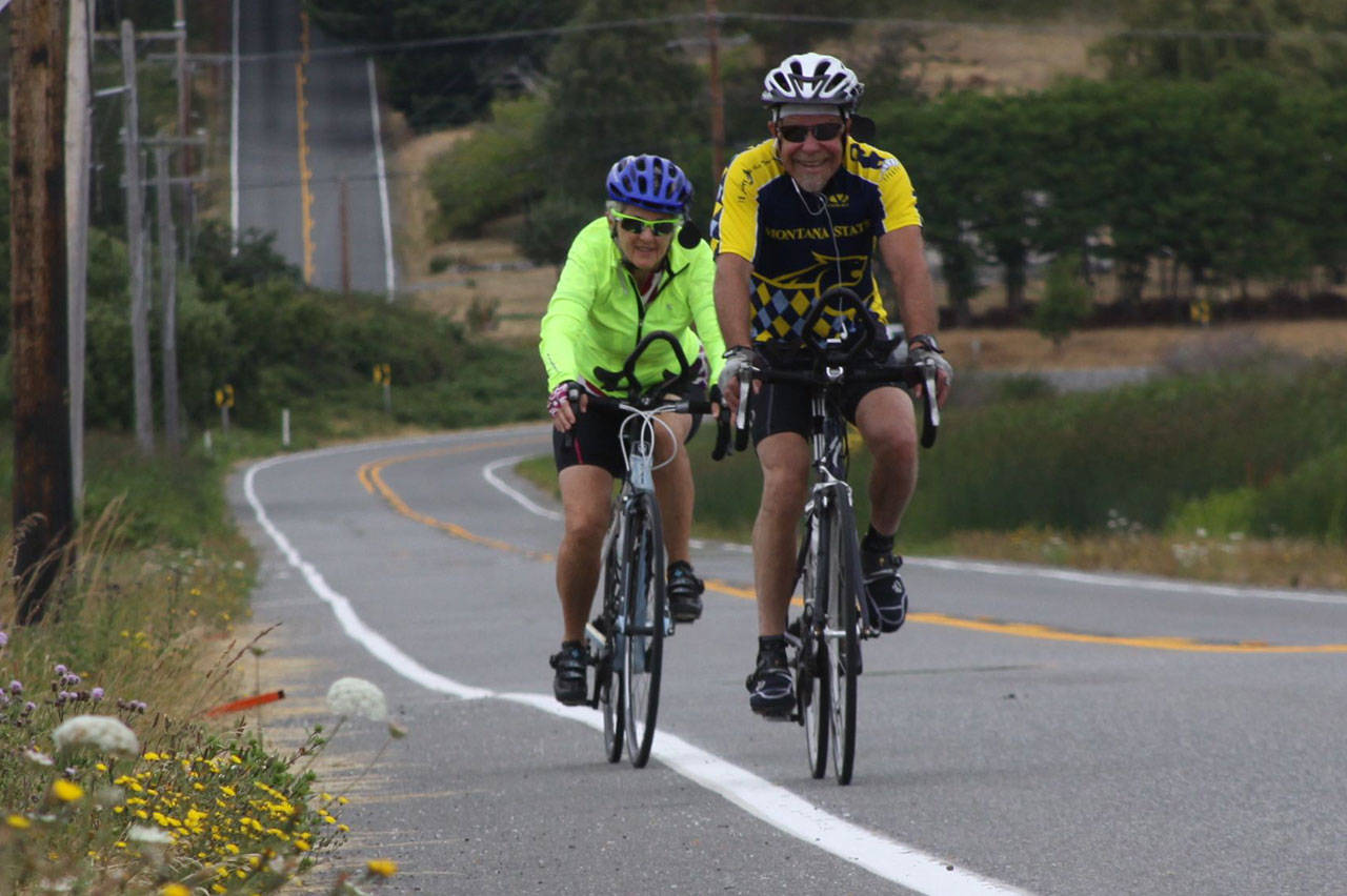 Ron Newberry photo &mdash; Steve Shapiro and his wife Debora Valis, of Langley, ride along Highway 20 near Crockett Lake during the final stretch of the Whidbey Camano Land Trust&rsquo;s second annual Sea, Trees, & Pie Bike Ride Sunday, July 23. In the background is Keystone Hill Road, part of the ride&rsquo;s 20-mile route.