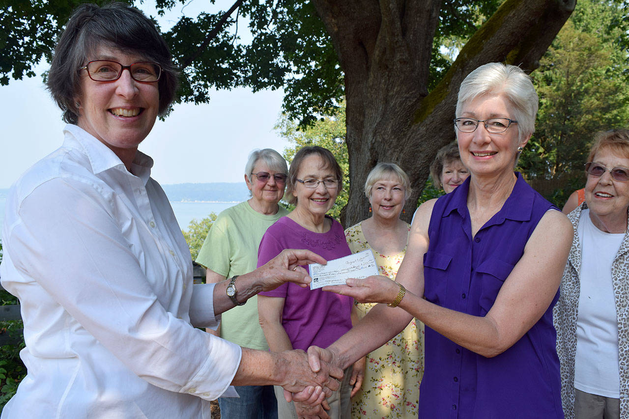 Kyle Jensen / The Record &mdash; Janice O&rsquo;Mahony, left, presents League of Women Voters Co-President Carla Grau-Egerton, right, with a check for $2,100 as League members look on.