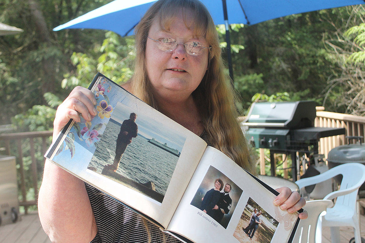 Evan Thompson / The Record — Kat Ersch holds up a photobook that includes pictures of her late husband, Bill Davison, a 22-year Navy veteran.