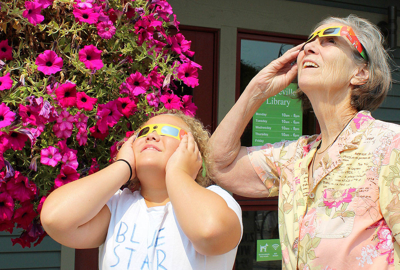 Patricia Guthrie / Whidbey News Group &mdash; Barbara Fournier and her great granddaughter Kayla Cooks try out glasses they&rsquo;ll be using in Oregon during Monday&rsquo;s 2017 Total Solar Eclipse. At a recent solar eclipse informational talk at Coupeville Library, Ruth and Andy Nielson of the Island County Astronomical Society talked about the features of the eclipse and the importance of wearing proper eye protection. Teens also made a nebula with jars and paints.