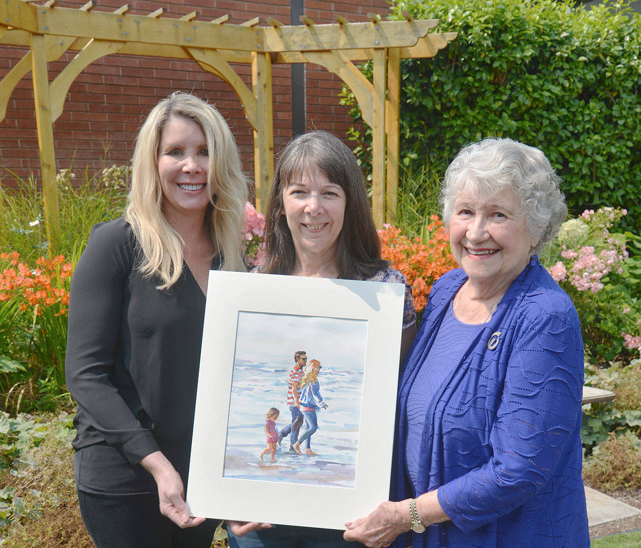 Contributed photo — Whidbey Telecom co-CEO Julia Henny (left) and Chairperson Marion Henny (right) pose for a photo with Valerie Mayer, whose artwork will appear on the cover of the Whidbey Telecom’s directory.