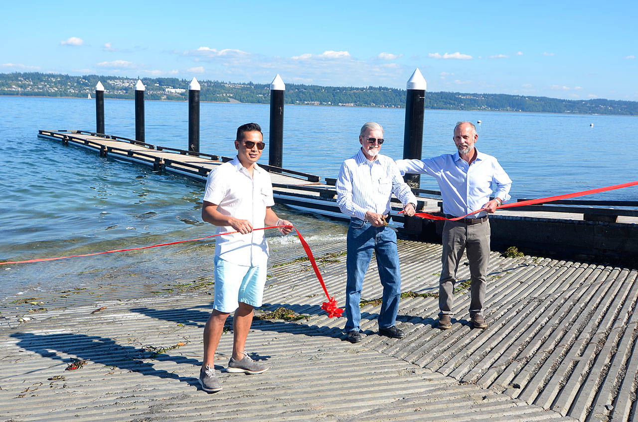 Justin Burnett/The Record — Port of South Whidbey commissioners Jack Ng, Ed Halloran and Curt Gordon participate in a ribbon cutting ceremony Thursday, officially opening the renovated Possession Beach Waterfront Park boat ramp.