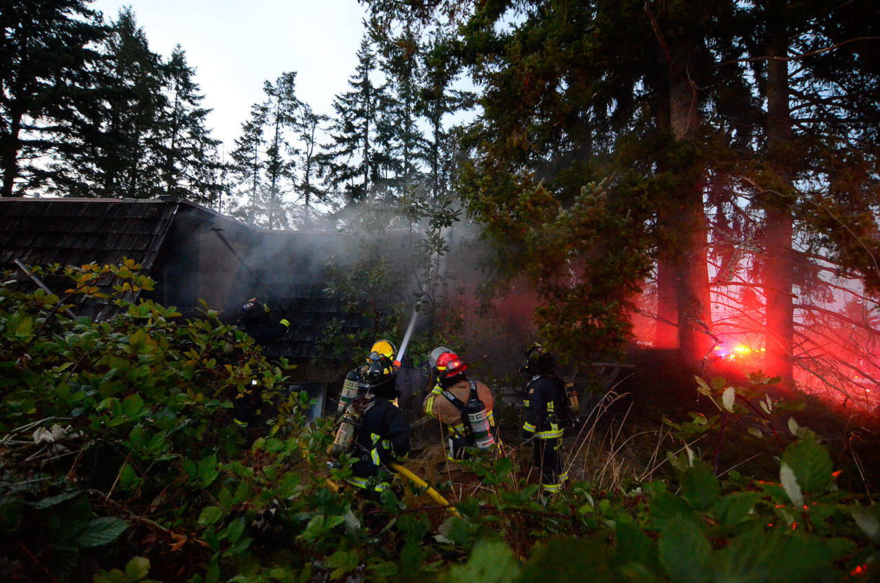 Justin Burnett/The Record &mdash; South Whidbey Fire/EMS firefighters work to extinguish a house fire on Honeymoon Bay Road on Wednesday evening. The fire was deemed &ldquo;suspicious&rdquo; in nature.