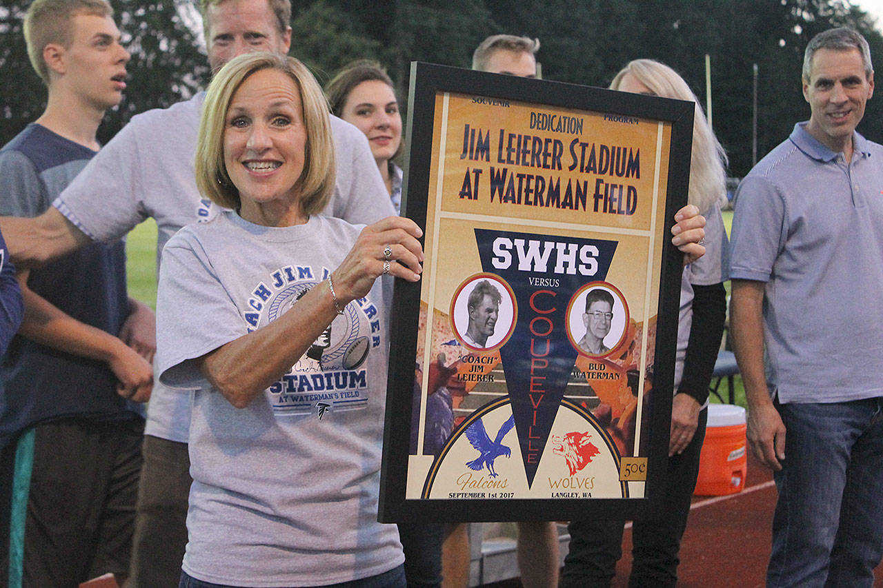 Evan Thompson / The Record — Lowana Dunckel, one of Jim Leierer’s daughters, holds up a plaque dedicated in her father’s memory, as well as Bud Waterman during a halftime ceremony on Friday night. South Whidbey High School’s stadium was renamed after the longtime sports icon who was known to many as “Coach.”