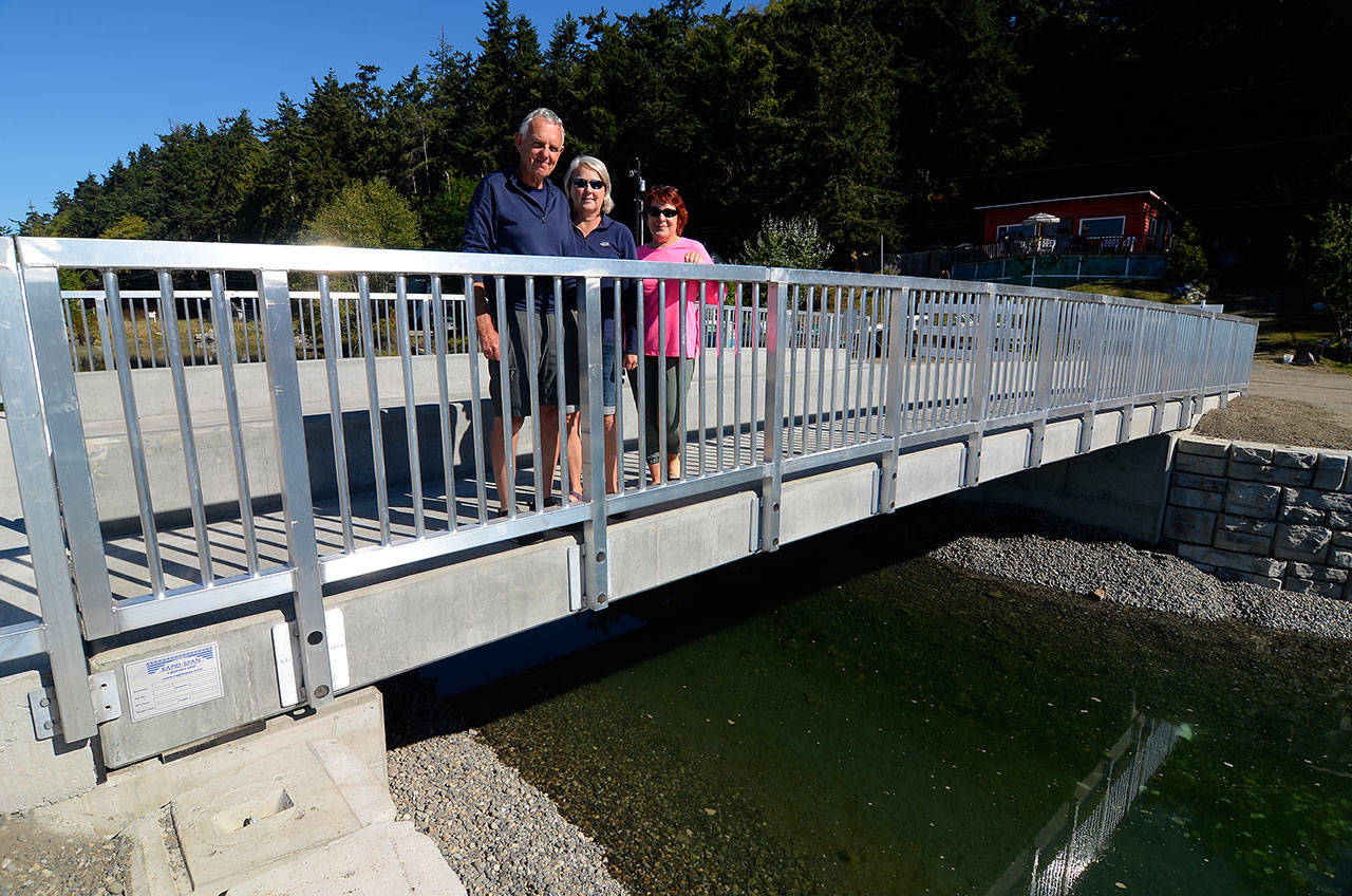 Justin Burnett/The Record — Lagoon Point Community Association President Duane Rawson, along with assistant secretary Christine Anderson and assistant treasurer Cheryl Kuss pose for a picture on the recently rebuilt Seashore Avenue Bridge. It replaced an older wooden structure and is one of two privately owned bridges in Island County.