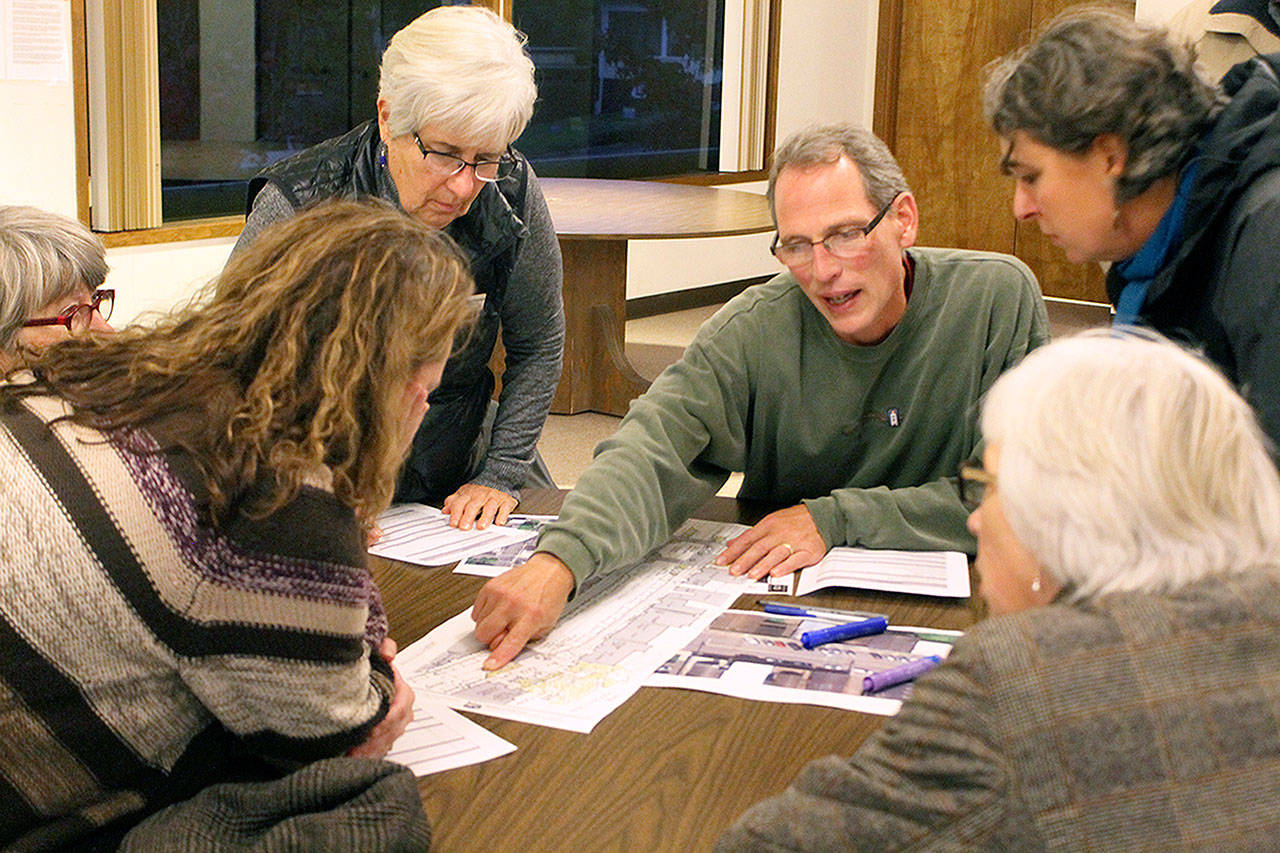 Evan Thompson / The Record — Langley resident Bret Bowers (center) points at a printed out sketch of a possible design of First Street during a public meeting on Wednesday night at Langley United Methodist Church.