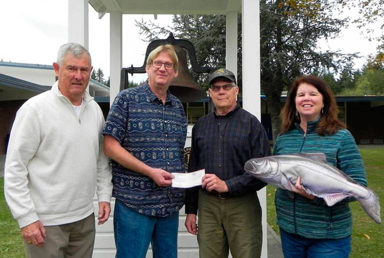 Contributed image — Steve Mooney of the Holmes Harbor Rod & Gun Club presents a $1,500 check to fifth grade teacher John LaVassar for the second year of Adopt-A-Grant sponsorship of the “Salmon in the Classroom” project, which teaches several grades of students about the life cycle of salmon and ecosystem stewardship. Bob Wiley of the South Whidbey Schools Foundation (left) and Lori O’Brien of Whidbey Island Watersheds were also present.
