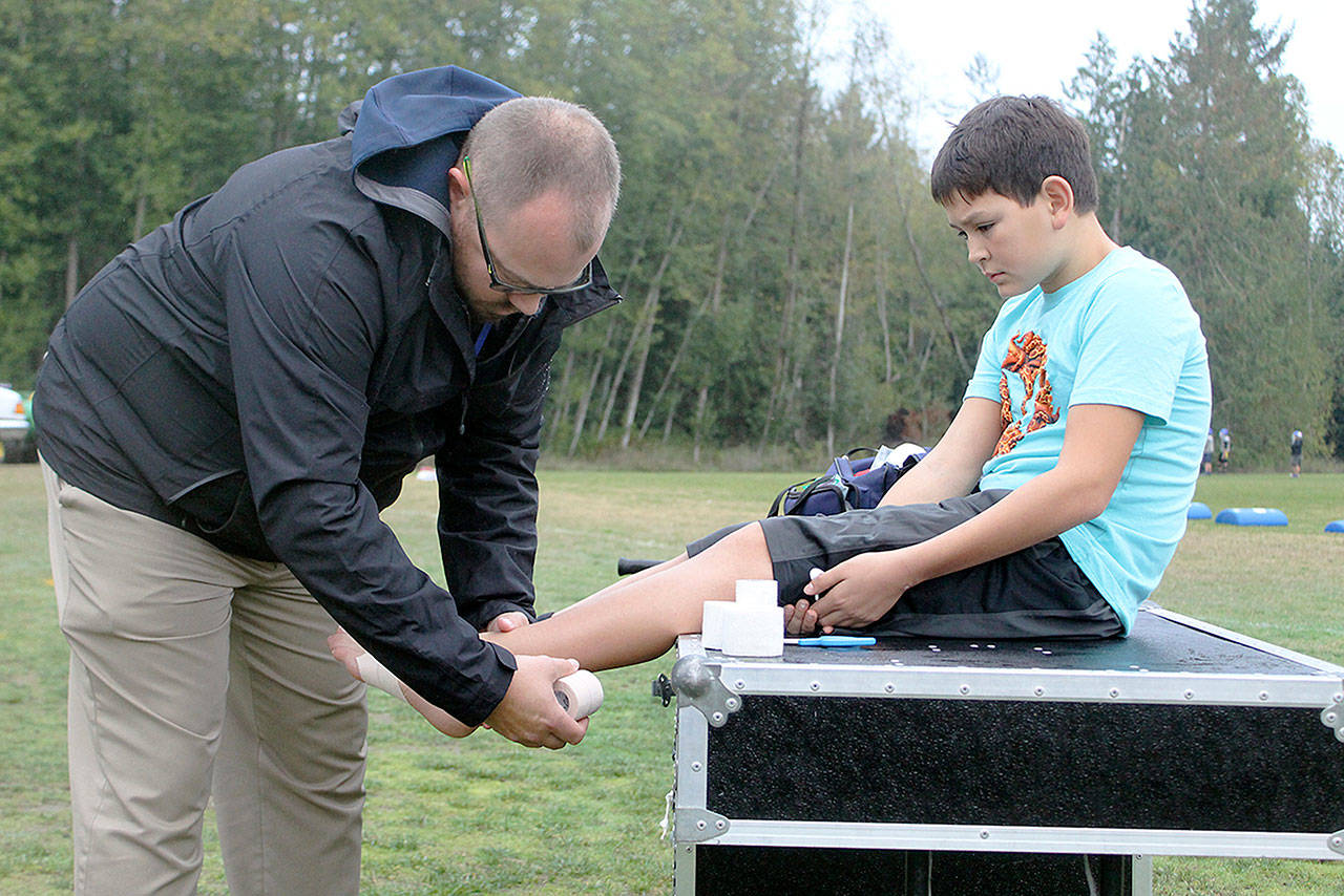 Evan Thompson / The Record  Nathan Welever, South Whidbey High Schools new athletic trainer, tapes South Whidbey Middle School seventh grader Lane Nichols ankle on Oct. 25. Welever is the South Whidbey School Districts first ever paid athletic trainer.
