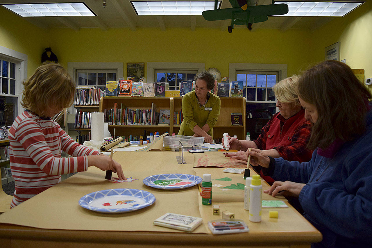 Kyle Jensen / The Record — Langley library associate Karen Achabal, center, shows people young and old creative ways to make their own wrapping paper.