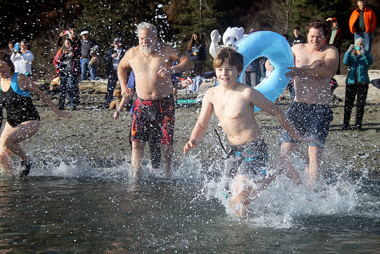 Evan Thompson / The Record — Dylan Paine, 10, and his dad Jon, holding the inner tube, were among 120 people who participated in the 14th annual Polar Bear Plunge on Saturday at Double Bluff Beach Park.