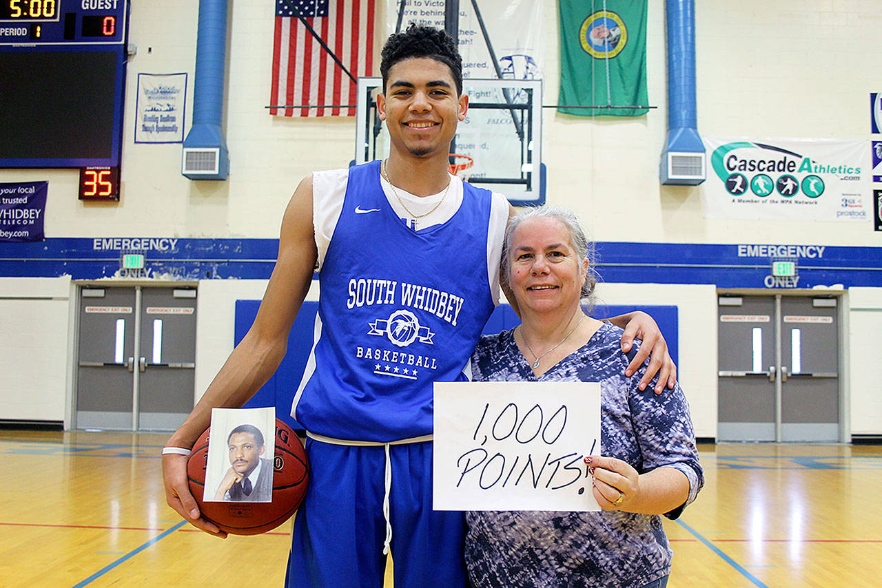 Evan Thompson / The Record — South Whidbey senior Lewis Pope holds a basketball with a picture of his late father, Henry Pope, with his mother Teresa Pope at his side. Pope recently eclipsed 1,000 points scored in his career for the Falcon’s boys basketball team.