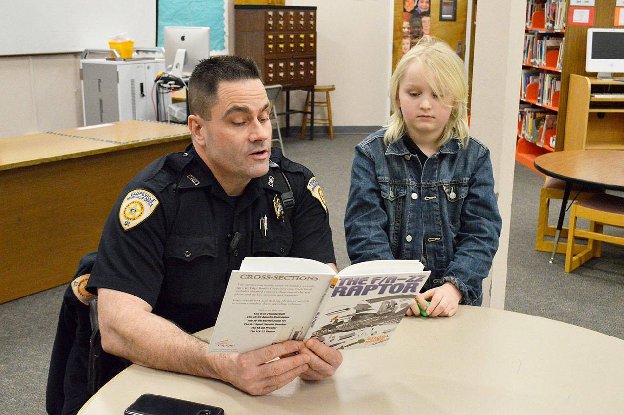 Laura Guido/Whidbey News Group                                Deputy Marshal Leif Haugen reads to second grader Colby Terry in the library of Coupeville Elementary School. Haugen is part of the recently launched “Bigs with Badges” program at Big Brother Big Sisters that pairs children in the community with law enforcement officers.