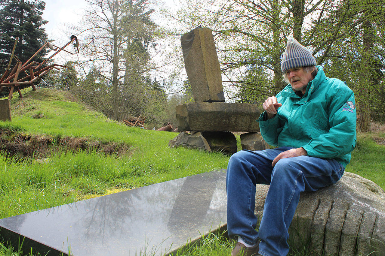 Hank Nelson sits near one of his installations at Cloudstone Sculpture Park, a 20-acre display near Freeland of his stone and steel work. Nelson and artist Sue Taves are being honored April 21 during International Sculpture Days. Photo by Patricia Guthrie/Whidbey News Group