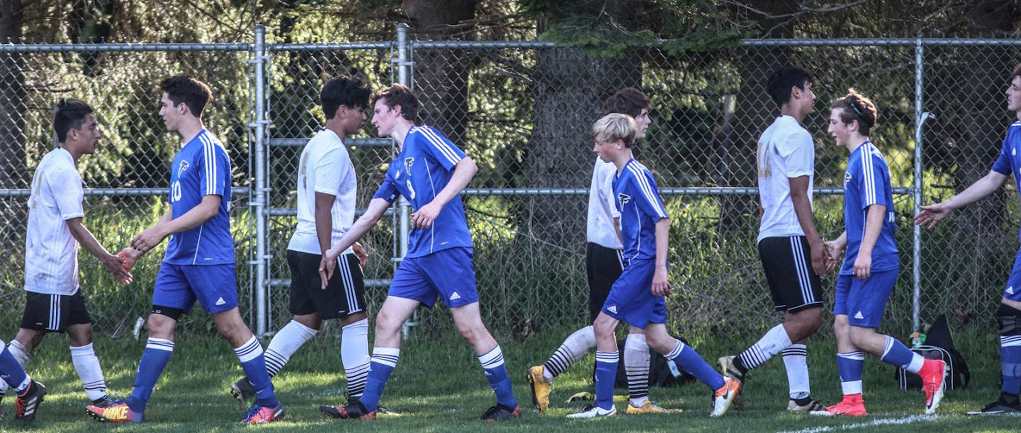 South Whidbey players (blue uniforms) shake hands with Meridian after winning Wednesday’s district tournament semi-final match. (Photo by Matt Simms)