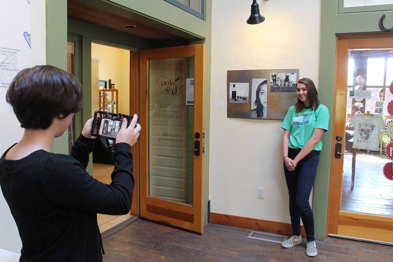Lily Zustiak takes a photo of Chandell Schoonover in front of “Consent,” the work of art Schoonover submitted to the show “Art with a Message,” at the Bayview Cash Store Hub gallery.                                Photo by Patricia Guthrie/Whidbey News Group
