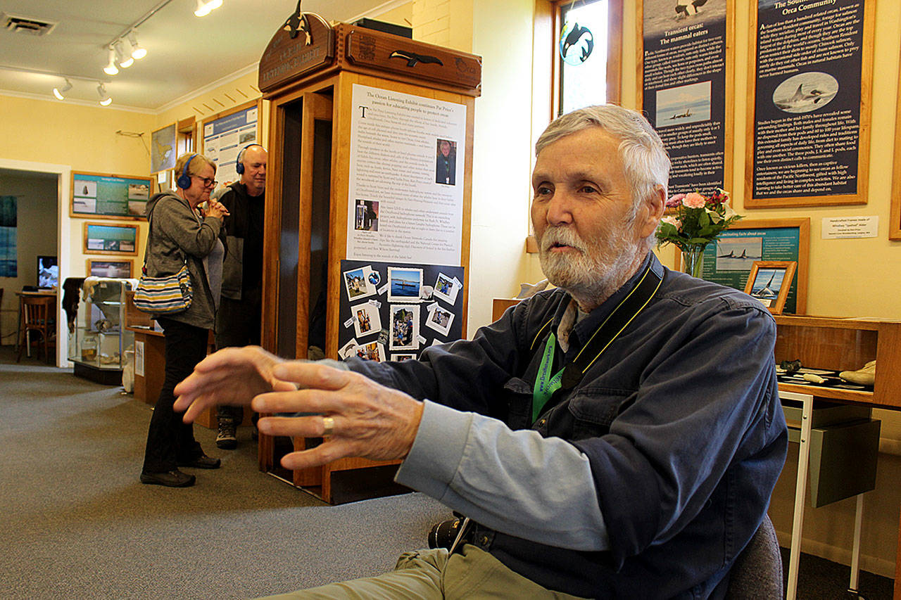 Howard Garrett of Orca Network talks about the new underwater listening booth at the Langley Whale Center while a couple listens through headphones in the background. The exhibits uses a renovated maple telephone booth. Photo by Patricia Guthrie/Whidbey News Group