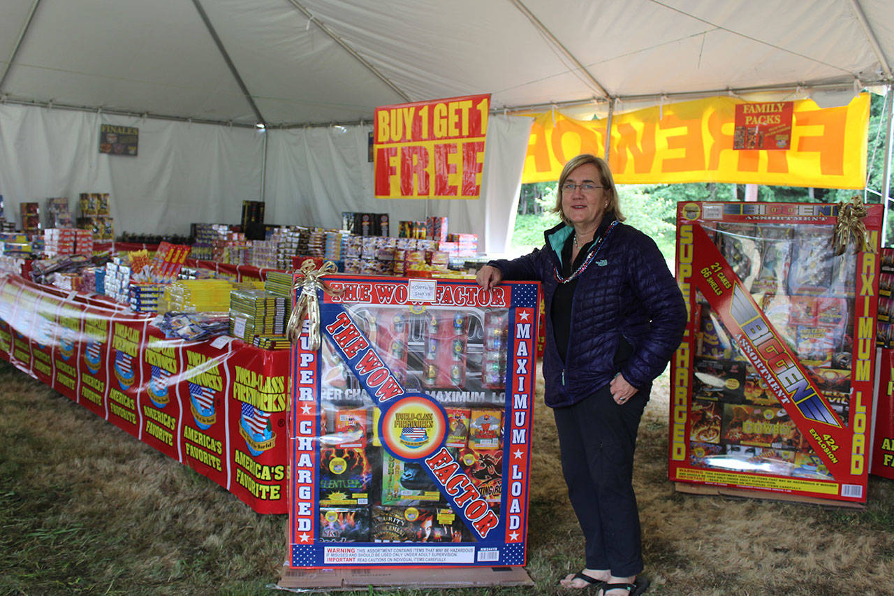 Sarah Szpak stands by the ultra big boxes of fireworks for sale at Big Dog Fireworks in Freeland. Since the tent opened Friday morning, Szpak said there’s been a steady stream of customers spending an average of $50.