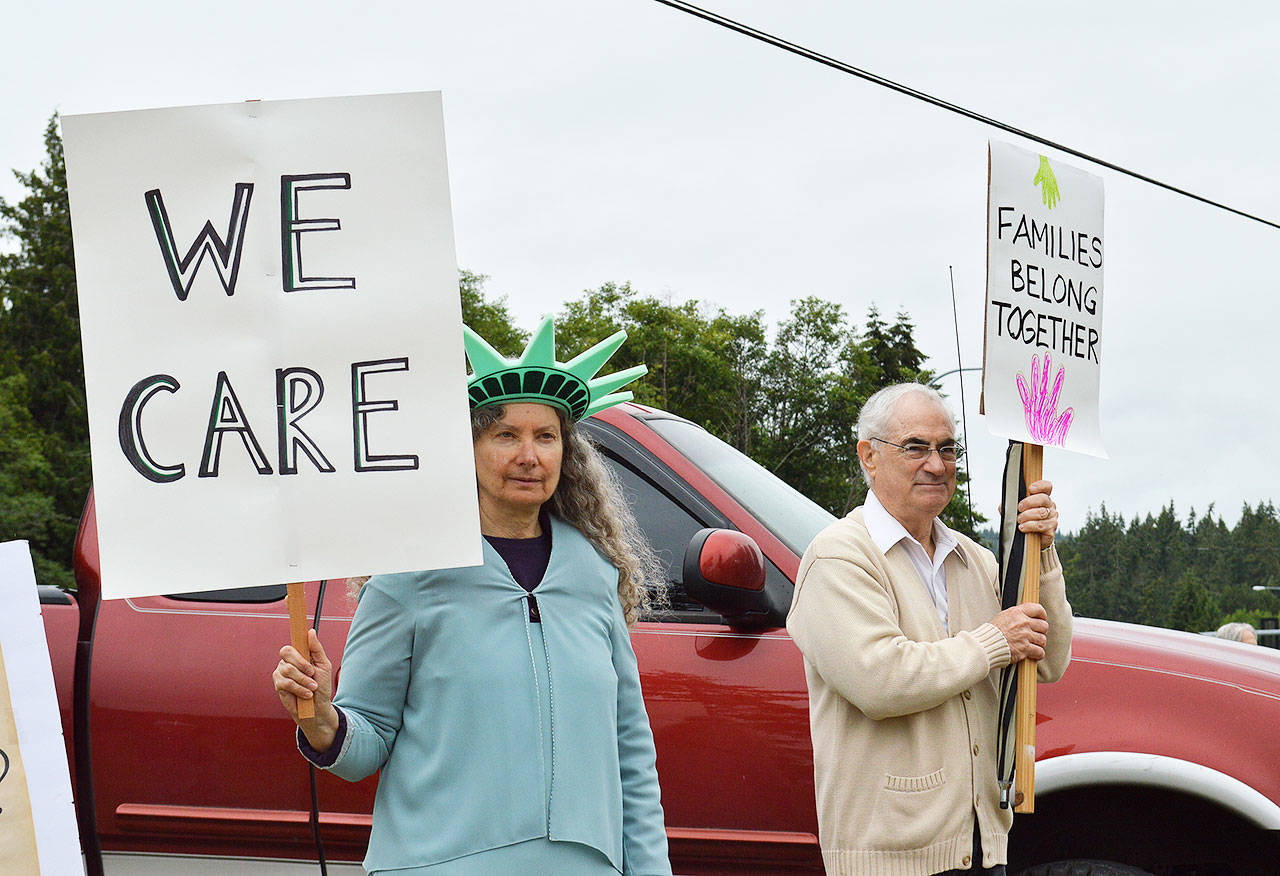Clinton resident Enid Braun and Rich Tamler of Freeland hold signs as part of a rally against the Trump Administrations zero tolerance immigration policy held Saturday morning at Bayview Park and Ride. Photo by Laura Guido/Whidbey News Group