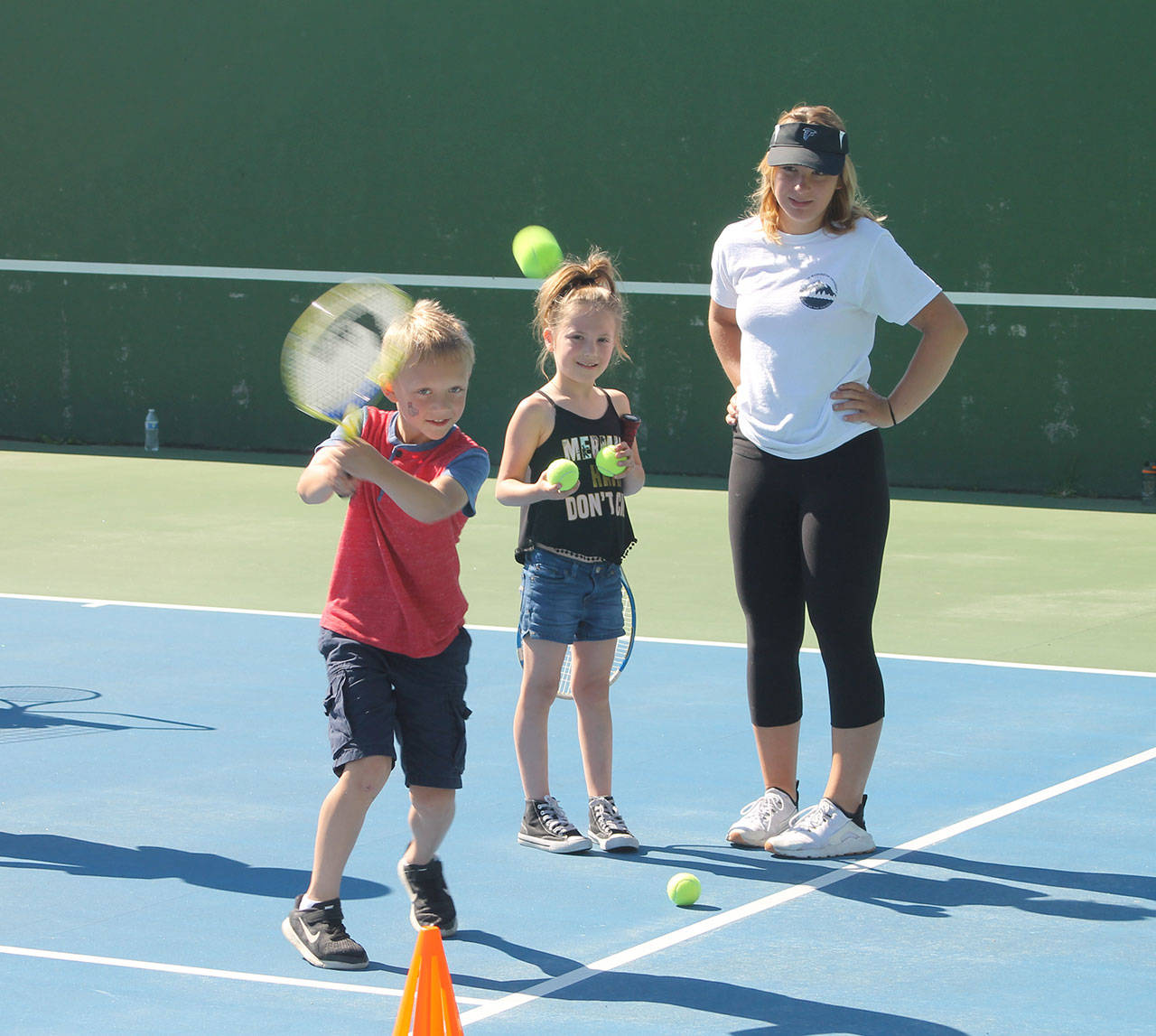 Alex Foode, right, watches a camper work on his backhand during a hitting drill Thursday. (Photo by Jim Waller/South Whidbey Record)