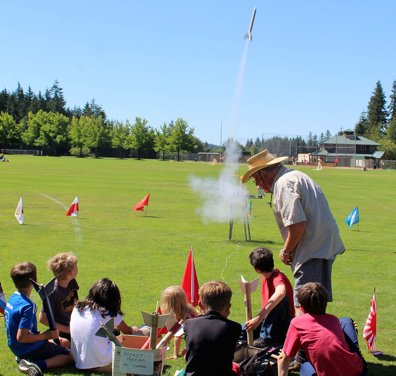 On a soccer field at Langley’s Community Park Thursday morning, one dozen kids launched model rockets they’d made under the guidance of longtime teacher, Leonard Good (right.) Photo by Patricia Guthrie/Whidbey News Group