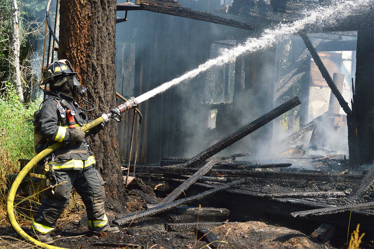 Firefighter Jeffrey Rhodes helps extinguish the last of the flames Wednesdays. Photo by Laura Guido/Whidbey News Group