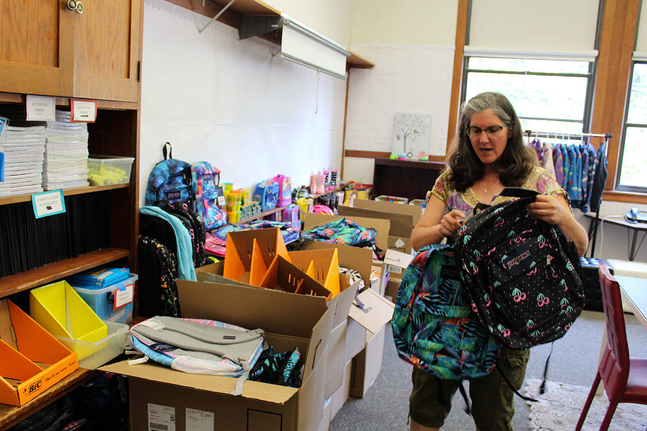 Mary Michell, family support specialist, goes through the dozens of new backpacks and other school supplies that are to be distributed to eligible South Whidbey and Coupeville students by Readiness to Learn Foundation. (Photo by Patricia Guthrie/Whidbey News Group)