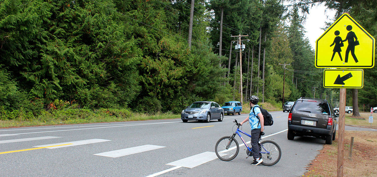 Flashing lights and bright yellow signs warn motorists to slow down to 20 mph in all school zones. However, it took awhile before one would actually stop to let this student cross the road in front of South Whidbey High School. The 20 mph speed limit is enforced 7 a.m. to 3 p.m. (Photo by Patricia Guthrie/Whidbey News Group)