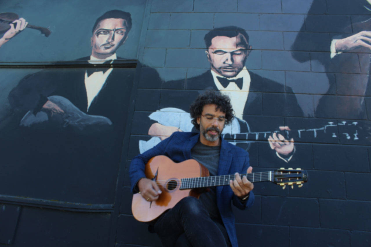 Troy Chapman plays in front of Langleys mural devoted to Django Reinhardt and DjangoFest Northwest. His band, Hot Club of Troy, performs Wednesday night at the music festival thats honoring founder Nick Lehr this year.The mural was painted by Matt Statz several years ago. (Photo by Patricia Guthrie/Whidbey News Group)