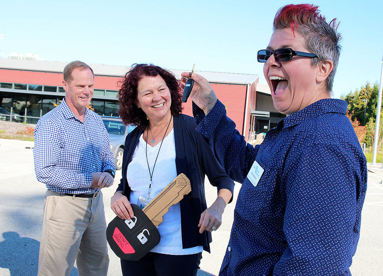 Mel Watson, of Island Senior Resources, shows off the key to the first van used in Island Transit’s RideLink program for nonprofits. Island Transit Executive Director Mike Nortier and Julie Lloyd, who coordinates the program, look on. Photo by Laura Guido/Whidbey News Group