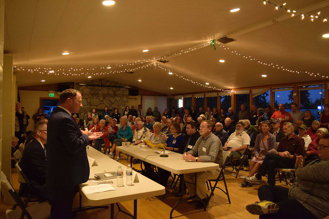 Rep. Dave Hayes speaks to an overflow, standing-room-only crowd packing Clinton Community Hall Monday night. Eight candidates answered questions presented by the League of Women Voters and Clinton Community Council. (Photo by Patricia Guthrie/Whidbey News Group)