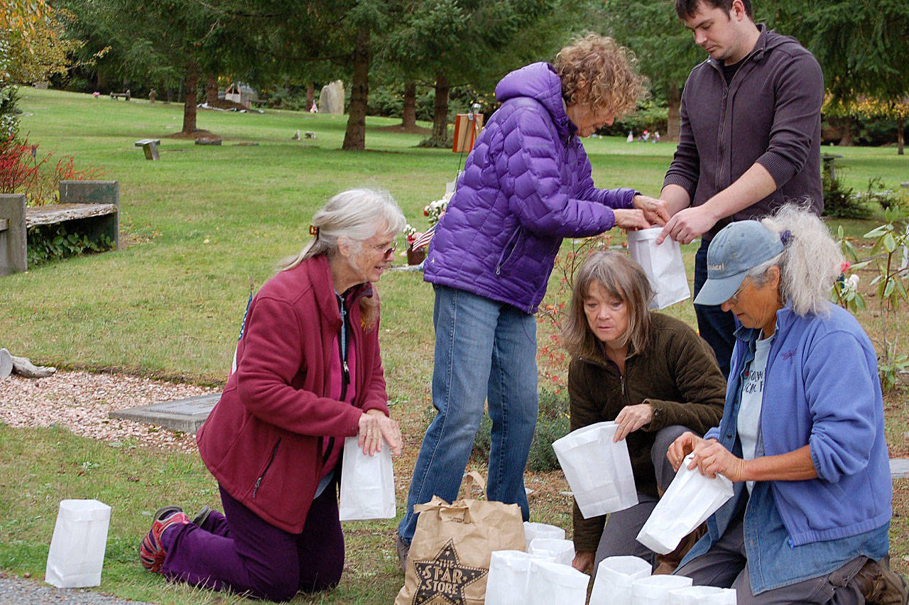 Preparing luminaries for All Souls Eve at the Langley Woodmen Cemetery are Meg Peterson, Thomas Biller, Serene and Lucinda Herring. Photo by Joan Soltys