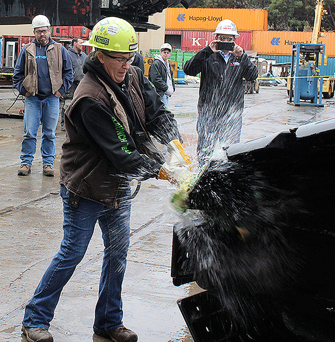 Photo by Patricia Guthrie/Whidbey News Group.                                Geri Downey christens a new crane at Nichols Brothers Boat Builders.