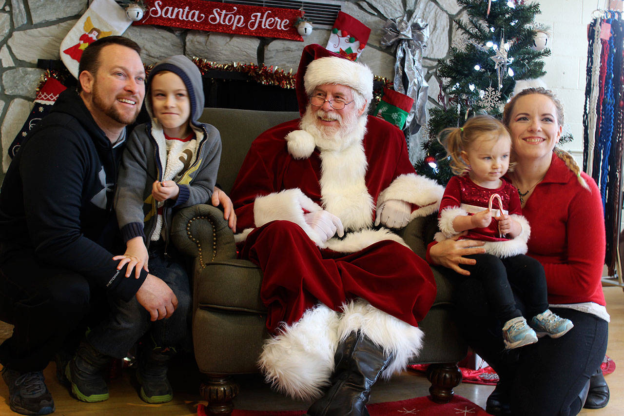Matthew and Amanda Brogan pose with their children, Tavin, 7, and Ayla, 2, for a free portrait with Santa Claus offered by the Clinton Chamber of Commerce. (Photo by Patricia Guthrie/Whidbey News Group)
