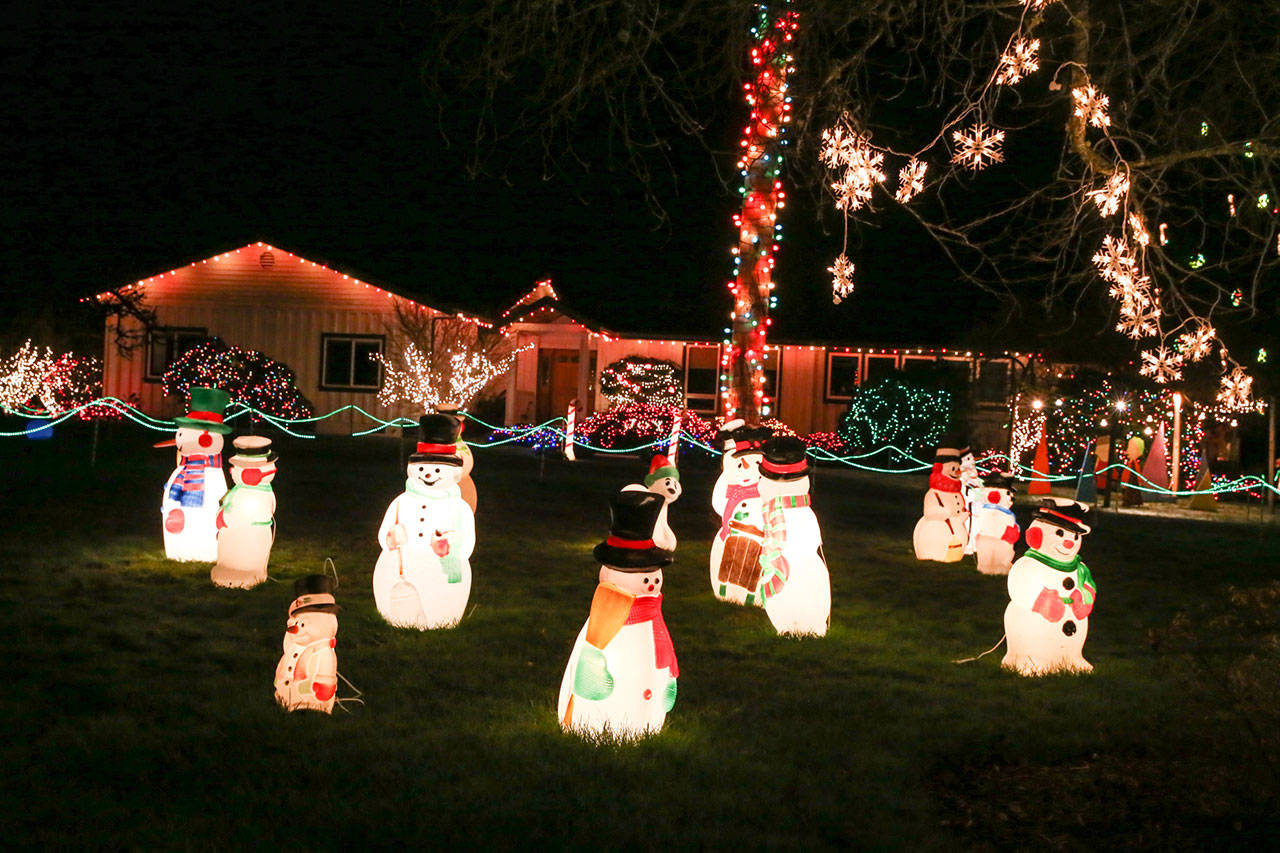 Blow-mold snowmen are among the first things visitors see when they visit the Becks’ annual Christmas light show. (Kevin Clark / The Herald)