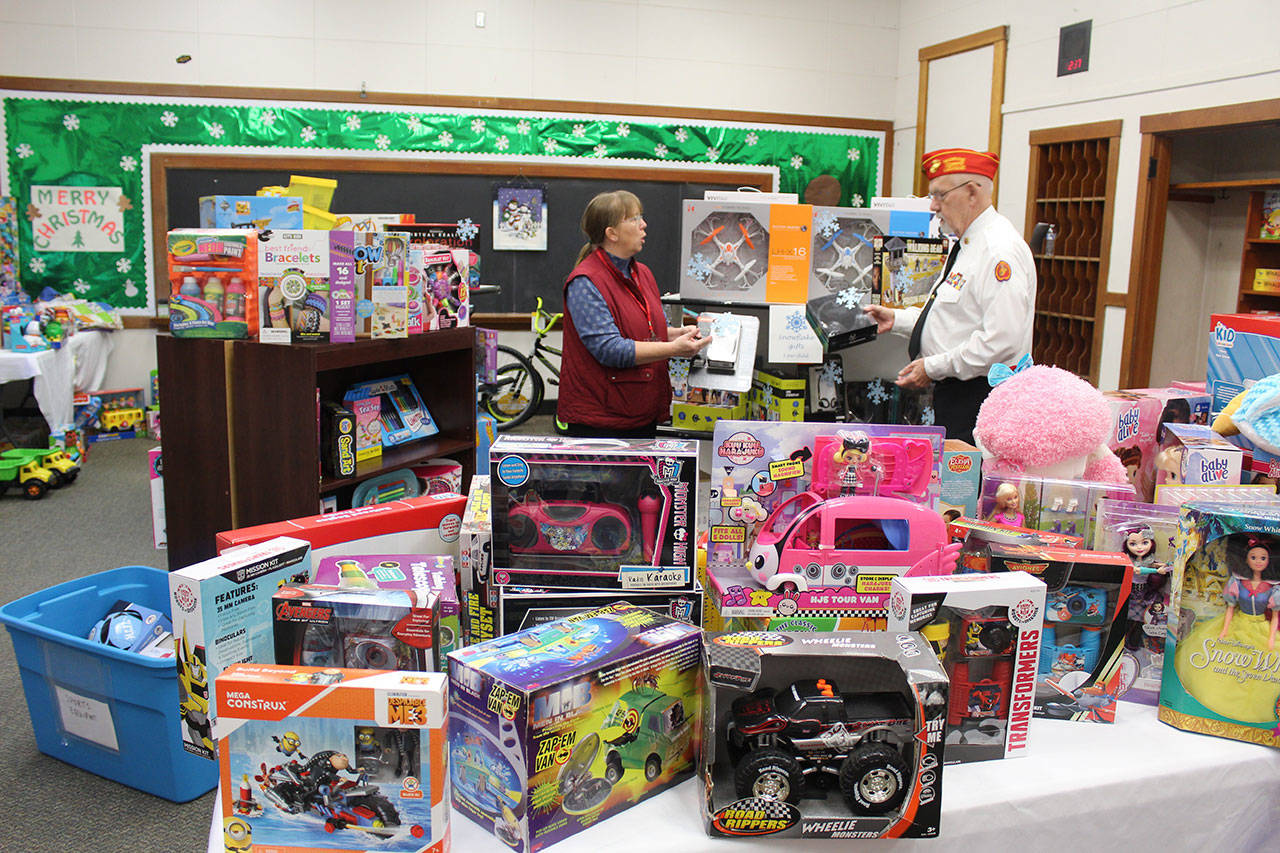 Shawn Nowlin, left, with Readiness to Learn Foundation and Marine Corps veteran Frank Thornton with Toys for Tots stand among hundreds of gifts given away to South Whidbey families the past month. (Photo by Patricia Guthrie/Whidbey News Group)
