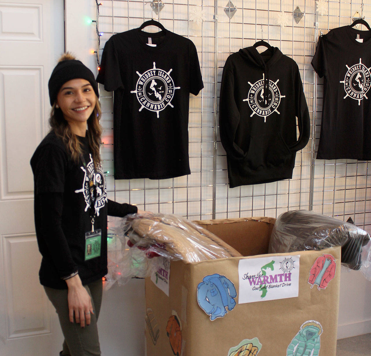 Budtender Megan Sinclair goes through coats recently donated for the homeless at Whidbey Island Cannabis Company in Freeland. The collection continues through January. (Photo by Patricia Guthrie/Whidbey News Group)