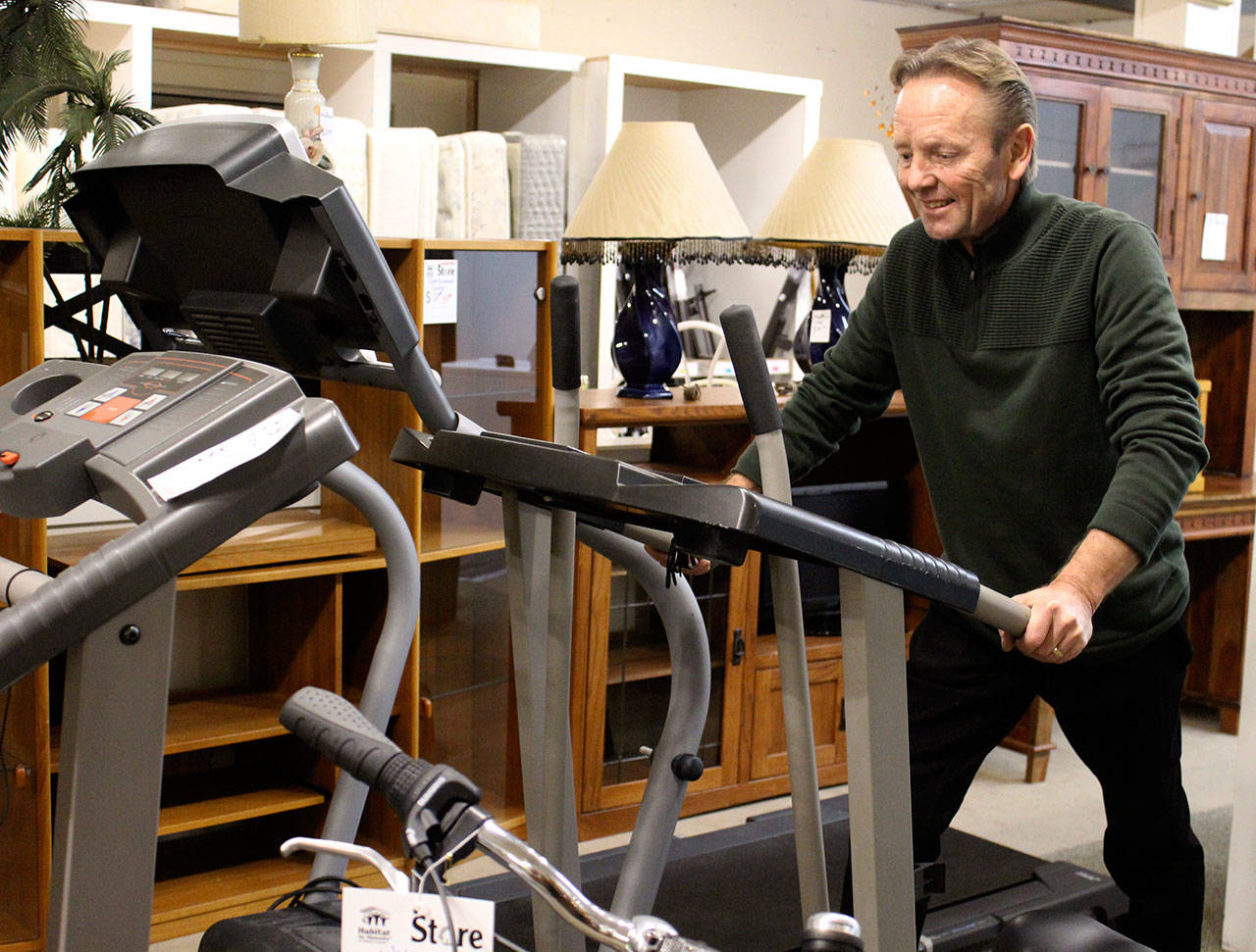Tony Persson, who oversees both Habitat for Humanity stores, demonstrates that home exercise equipment is sometimes donated and put up for sale. He tries out a treadmill at the Oak Harbor location. (Photo by Patricia Guthrie/Whidbey News Group)